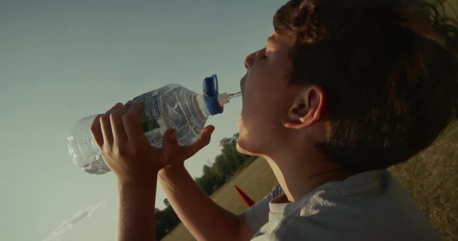 Boy in a field drinking water