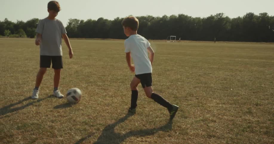 Two kids are practicing kicking a soccer ball to each other