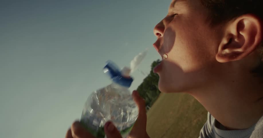 Boy drinks water from a bottle outdoors