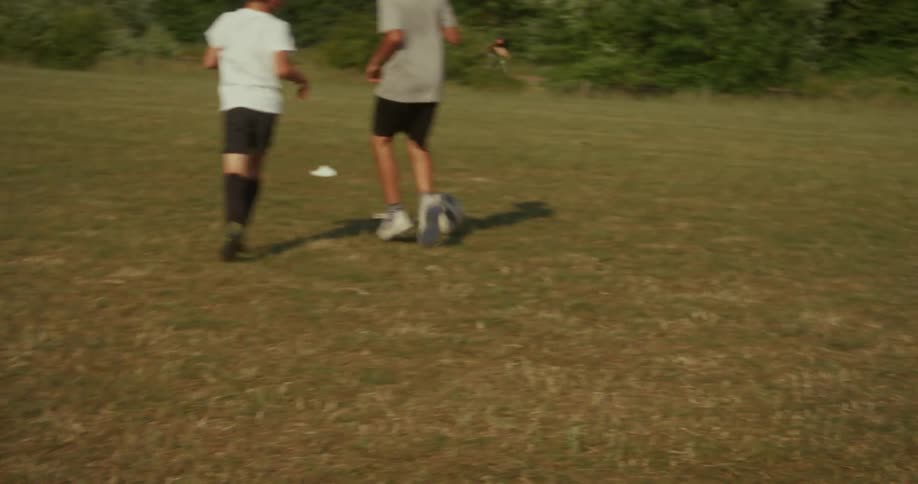 Two kids playing soccer on a field at midday