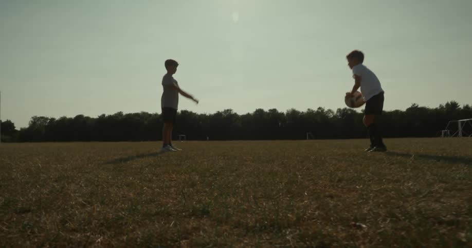 During the spring season two kids are throwing a soccer ball