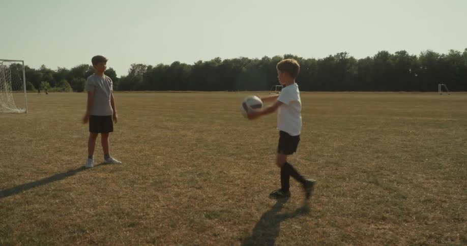 Two kids are throwing a soccer ball outdoors in spring