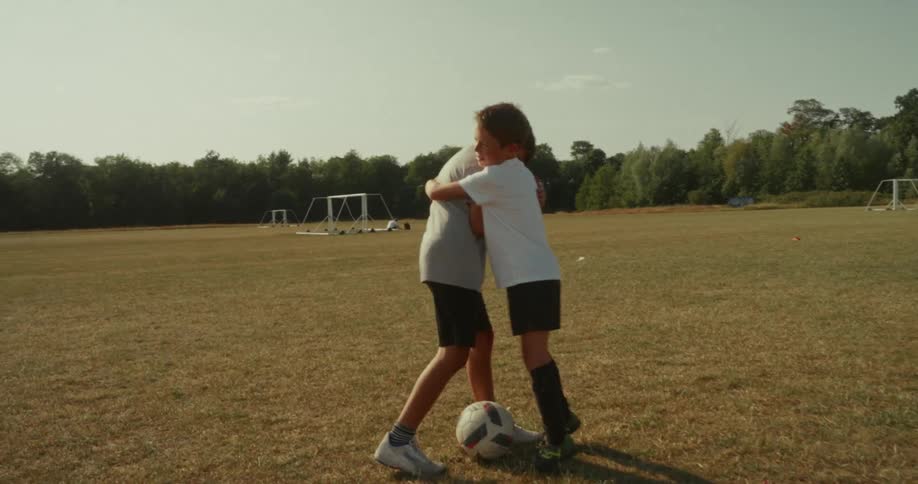 Two kids are celebrating a soccer match together on the field