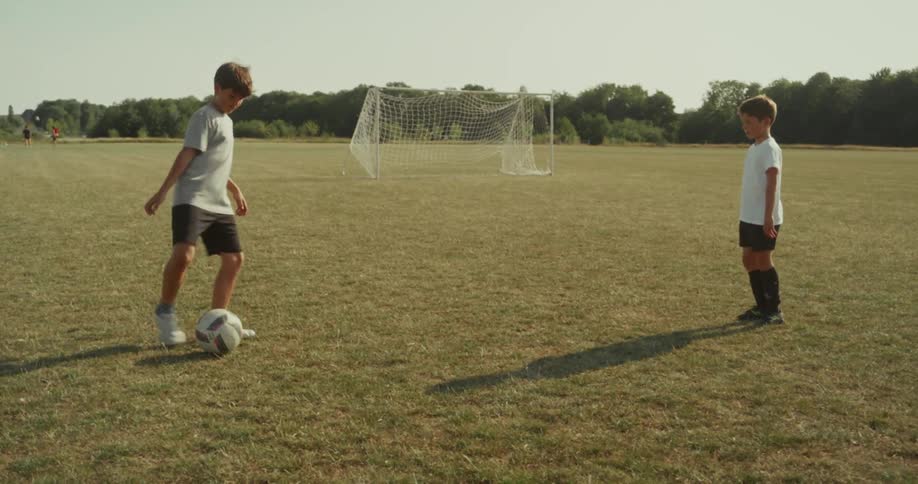 Two kids practicing soccer at a park during spring season