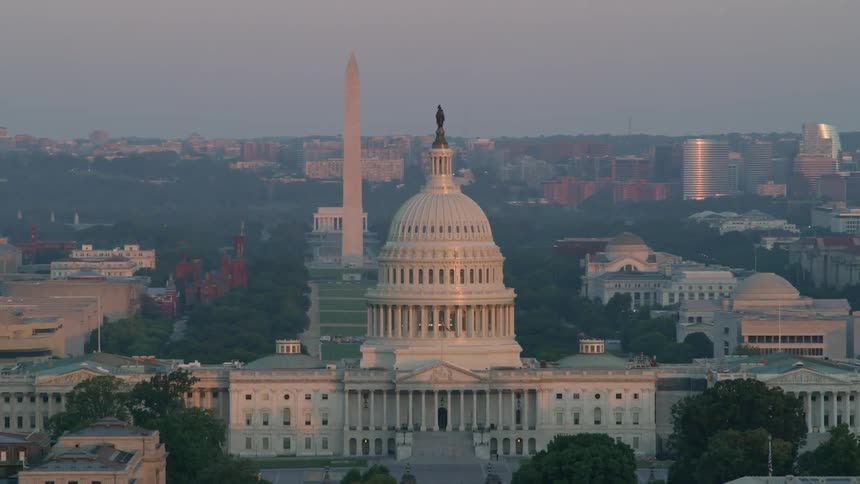 The sunlight reflects on the capitol building and washington monument