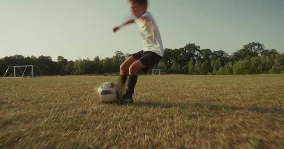 Boy kicking a ball in a field