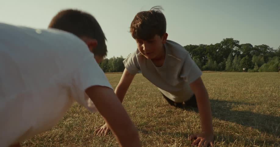 Two boys in a field touching hands and doing pushups
