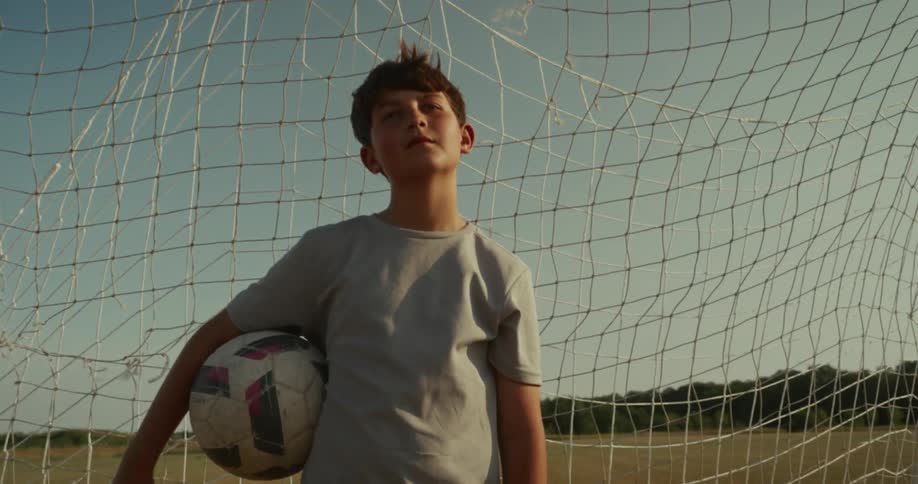 Boy in a goal on a field holding a ball