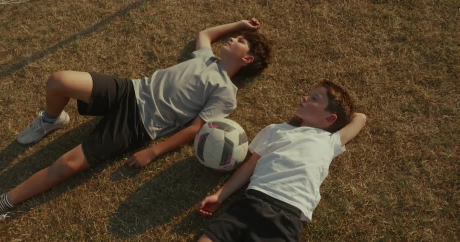 Two boys lying in a field in the late afternoon