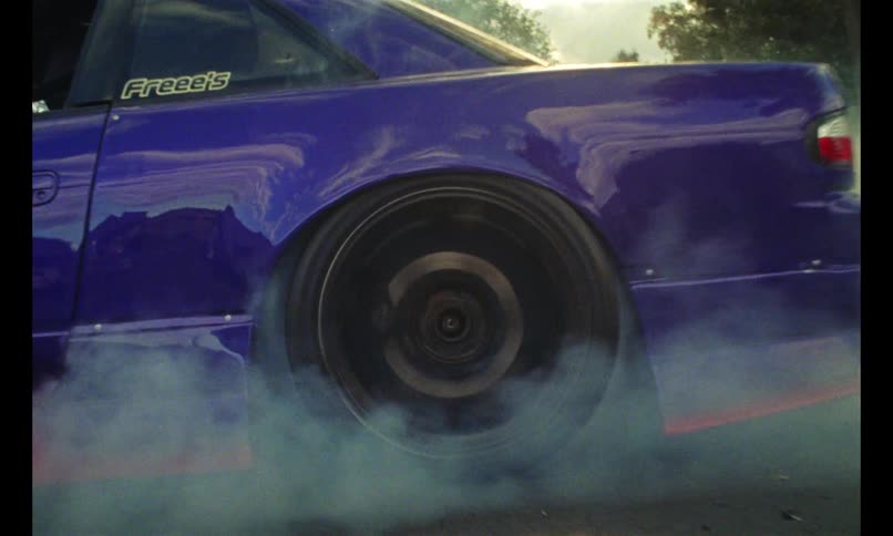 Driver performing a burnout in a sports car on a road