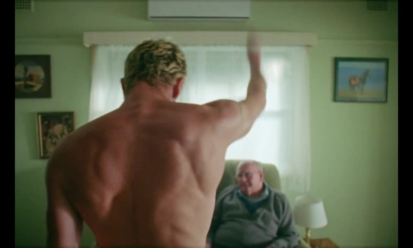 Shirtless man dancing in living room for elderly couple sitting on couch
