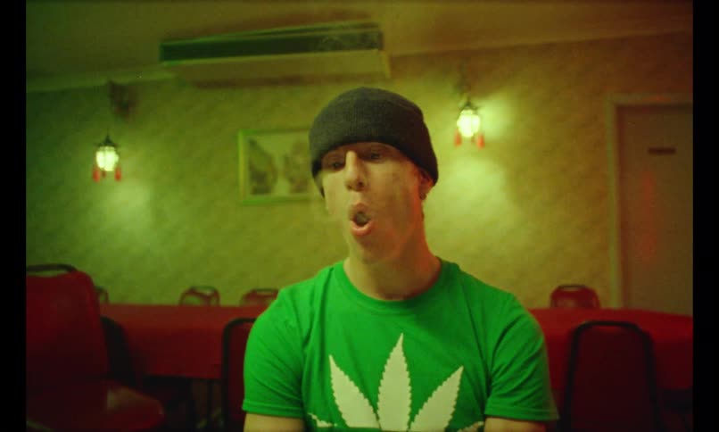 A man sits alone in a restaurant blowing smoke as various dishes are served in front of him