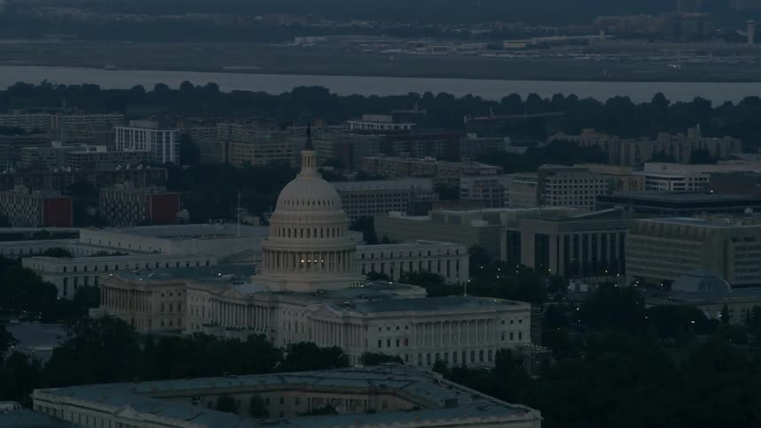 The u.s. capitol building stands amidst other buildings at dusk