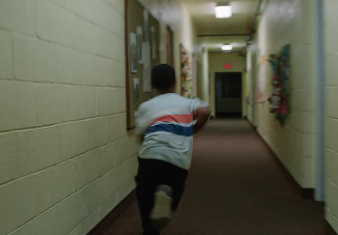 The student runs down the hallway in school