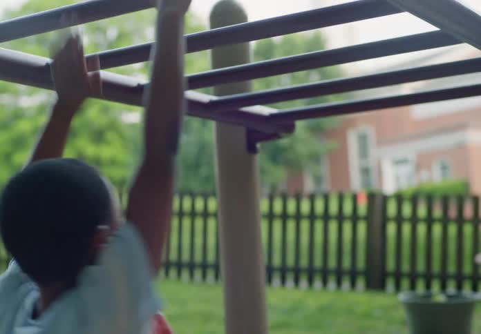 A child in a play area swinging on a pole
