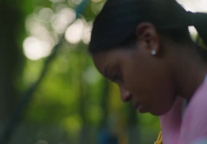 A closeup reveals a young girl with dark hair sitting on a swing appearing deep in thought she then pulls out her phone and begins to look at the screen her expression still contemplative