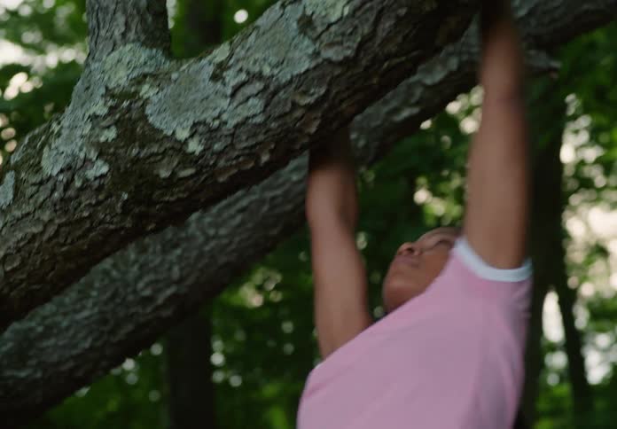 A girl hangs from the branch in the forest