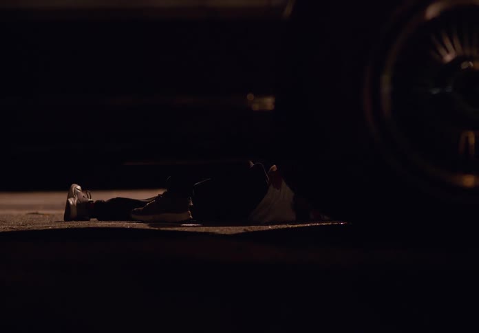 An injured person is lying on the ground near the car
