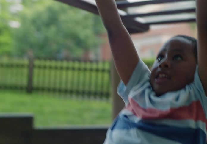 A young boy climbs on monkey bars with determination at an outdoor playground