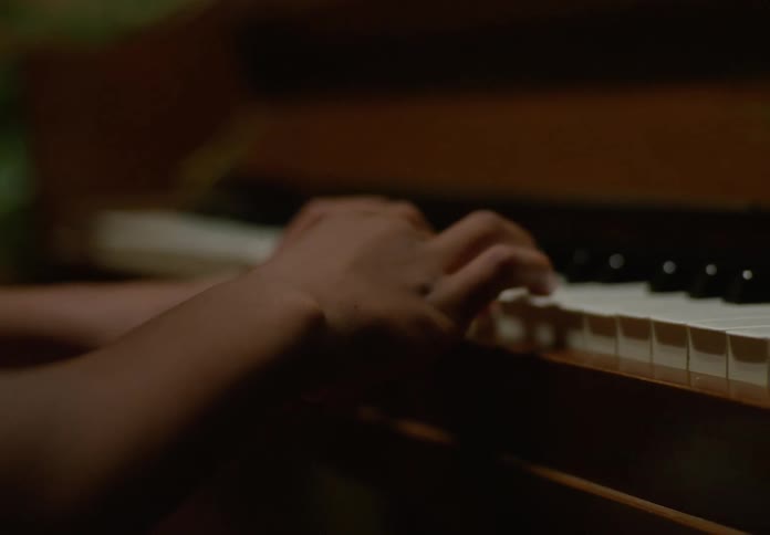 A child hands are shown closely playing piano keys