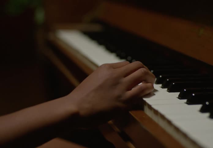 A girl child playing piano keys in a closeup shot