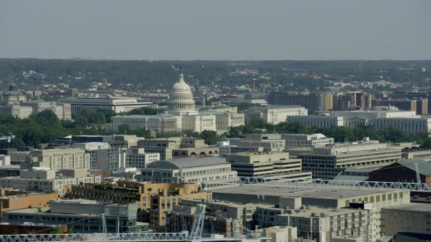 The u.s. capitol building stands amidst other buildings on a hazy day