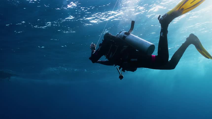 A scuba diver is ascending or adjusting equipment underwater in the open ocean