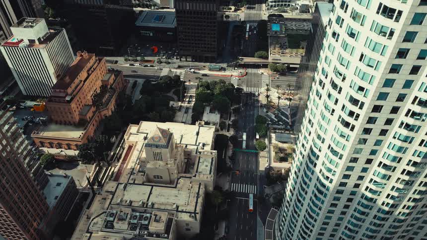 An aerial view shows tall buildings and city streets in a downtown urban area