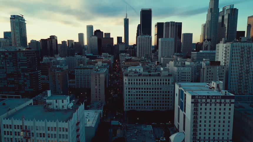 A wide aerial shot of a modern urban skyline at sunset