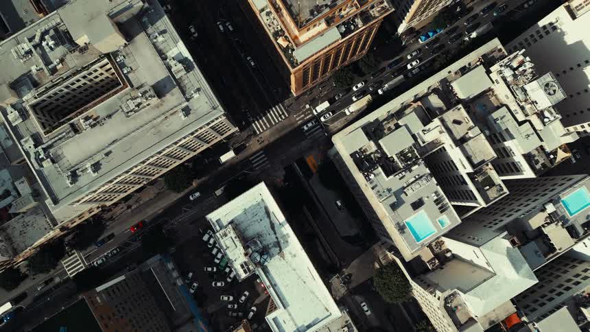 A dense cluster of city buildings surrounds a major intersection and sparse midday traffic