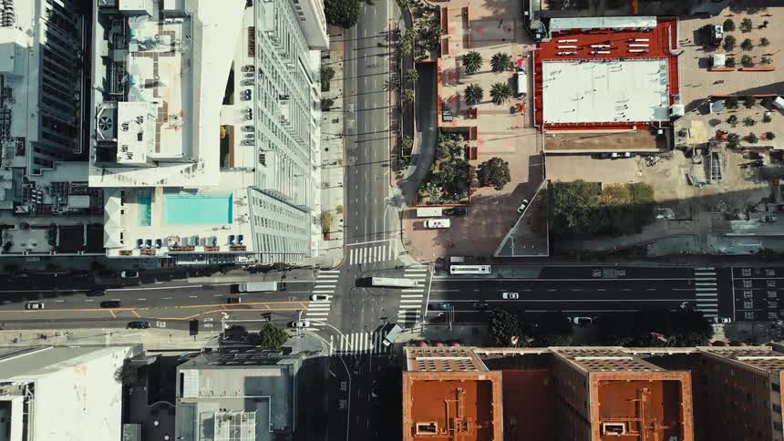An aerial view of the city shows cars moving along the streets at midday