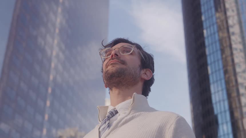 The man is looking up in the city