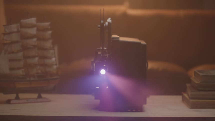 A vintage film projector sits on a table its bright light casting a beam forward ready to display old memories to its left a miniature ship model adds to the nostalgic and classic ambiance of the scene