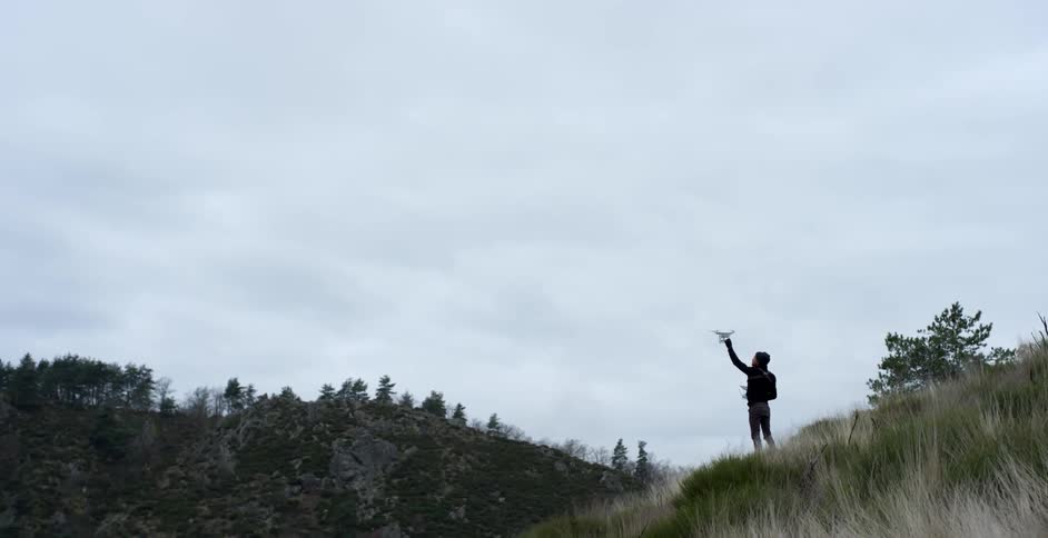 A man reaches up towards a drone