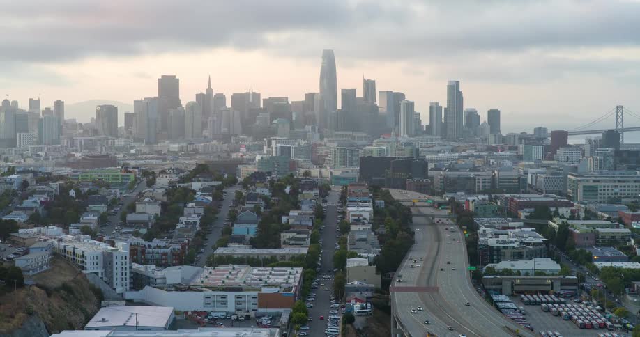 Aerial view of san franciscos skyline rising above a highway winding through foreground neighborhoods