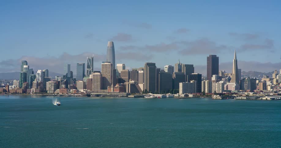 A city skyline with numerous tall buildings stands across a wide body of water with a boat moving towards the left