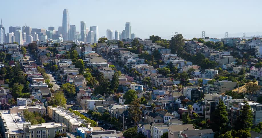 San franciscos downtown skyline rises in the distance behind rows of colorful residential buildings