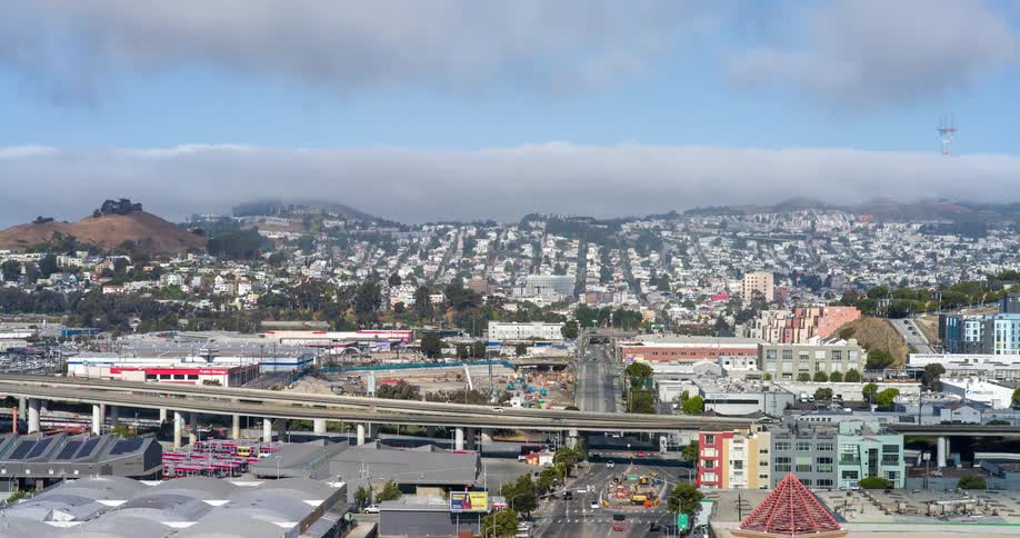 A city view at midday shows an overhead bridge with a series of cars passing by