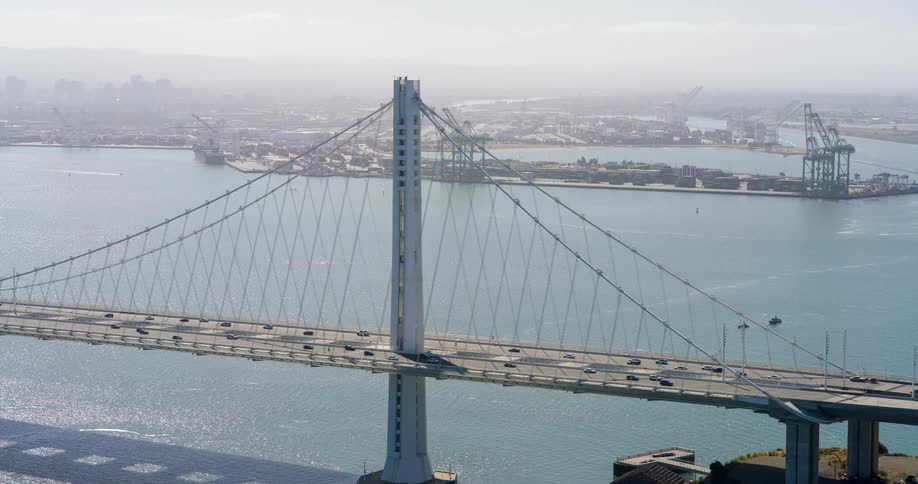 Bridge over the sea with vehicle traffic and an urban city in the background
