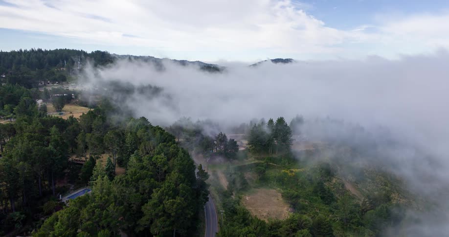 Aerial landscape with fog and scattered houses between mountains with trees