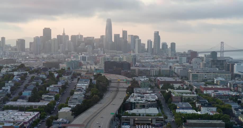 A city view at midday shows an overhead bridge with a series of cars passing by
