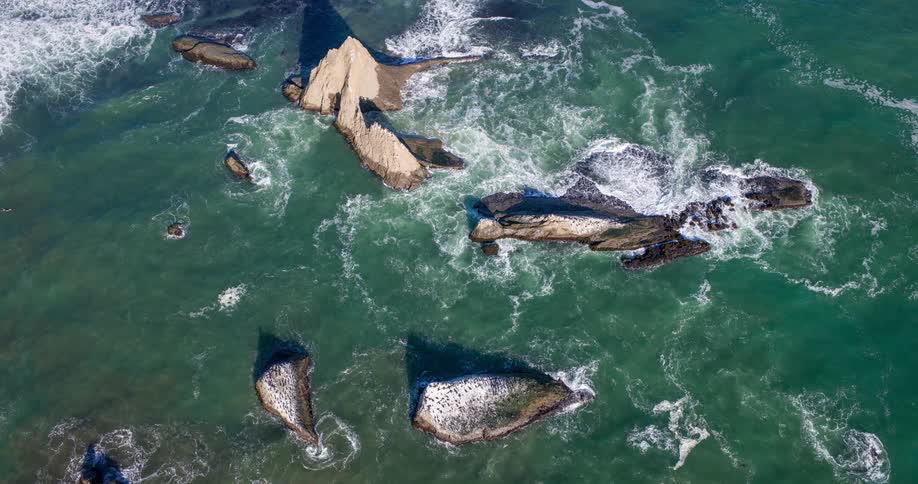 Aerial view of large rocks in the greenish ocean