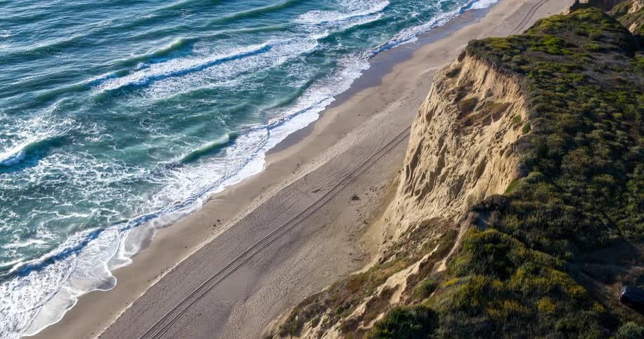 A shoreline with ocean waves crashing against it at midday