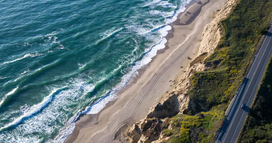 Cars drive along a highway near the ocean