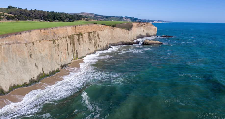 A cliff lines the shore as waves crash