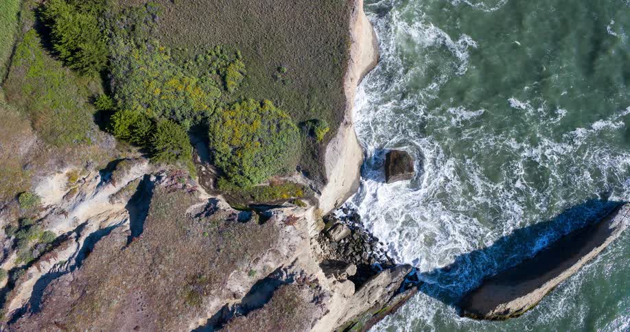 The waves are crashing against the rocks below