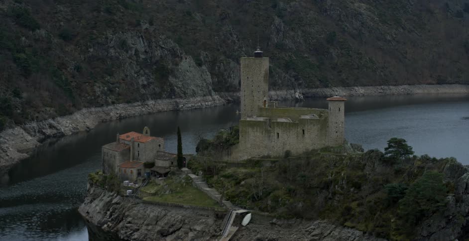 Stone buildings sit near the shore on a hill