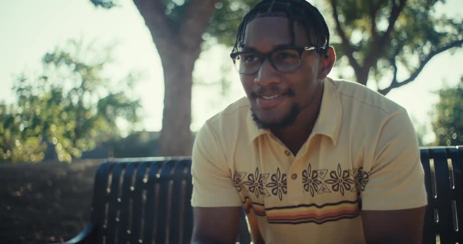 Man sitting on a bench outdoors with happy expression and holding a smartphone