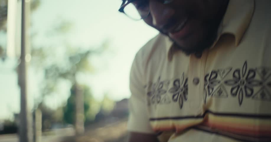 A closeup shot focuses on a persons hands holding a smartphone with their thumbs actively scrolling on the screen the background is blurred suggesting an outdoor setting with a hint of trees