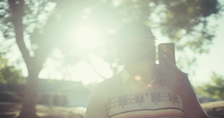 Close up of a young black man smiling while making a phone call outdoors during daytime